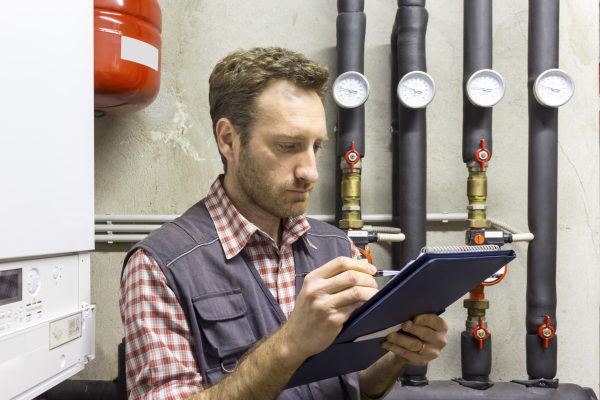 plumber-writing-clipboard-while-inspecting-heating-system