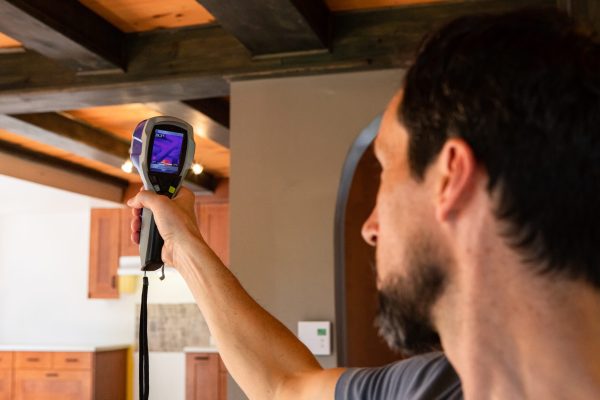 An indoor environment quality IEQ assessor is seen at work, using a digital thermography device during an in-depth inspection